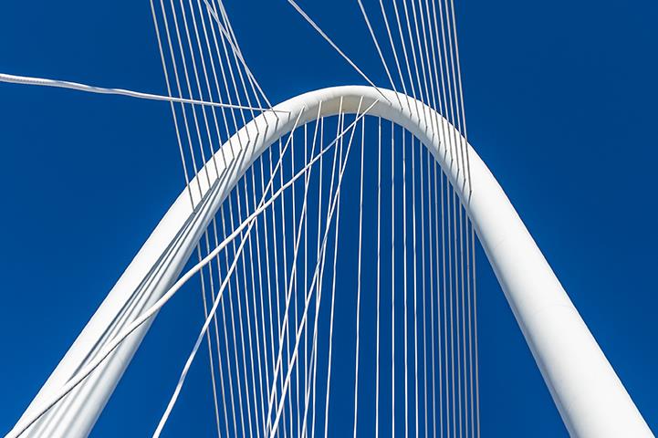 bright white suspension bridge against a deep blue sky