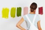 Woman facing wall with color samples painted on