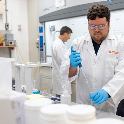 Man wearing goggles using a pipet to fill a test tube