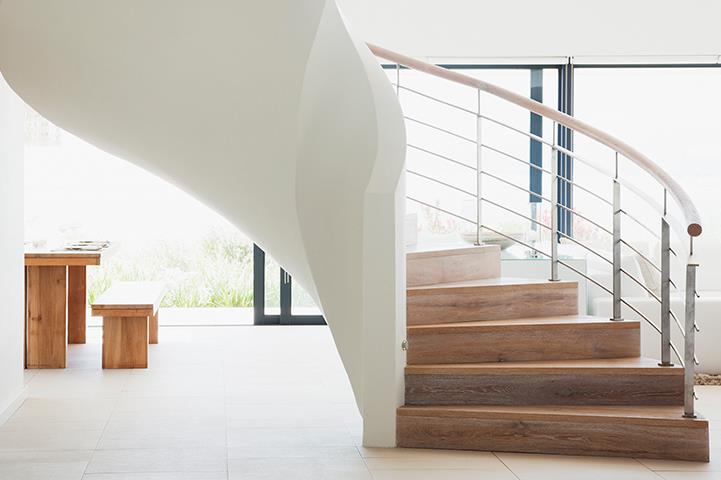 curving white standalone staircase in a bright white home