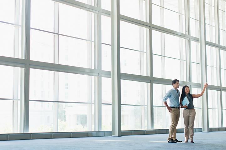 man and woman standing in front of large wall of floor to ceiling windows talking