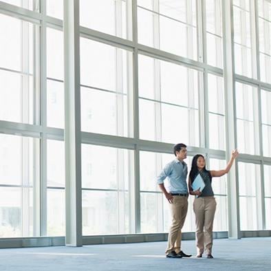 man and woman standing in front of large wall of floor to ceiling windows talking