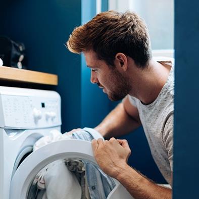 man putting laundry into dryer