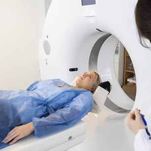 patient lying on bed of an MRI machine with doctor to the side