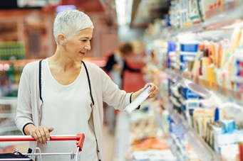 plder smiling woman shopping for groceries in the dairy aisle