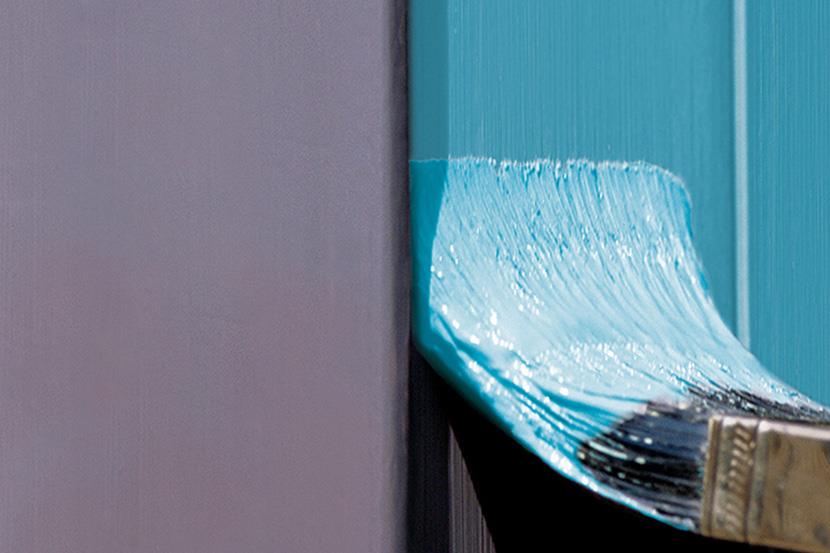 paintbrush covered in blue paint painting over plumb colored wall