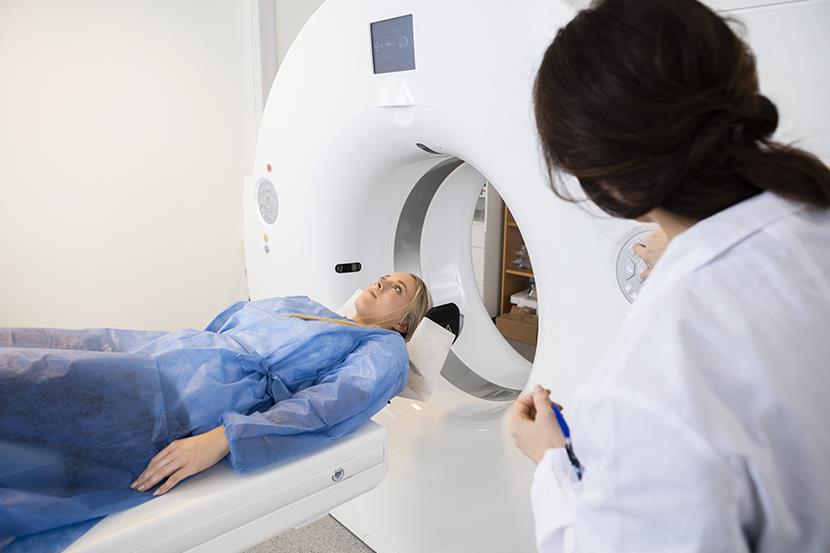 patient lying on bed of an MRI machine with doctor to the side