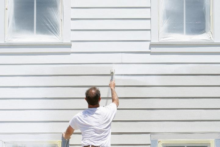 man painting the side of a house