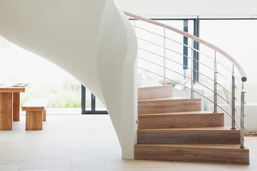 curving white standalone staircase in a bright white home