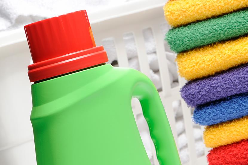 laundry detergent bottle in front of stack of colorful towels