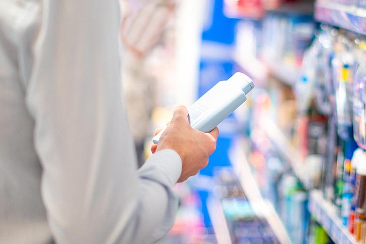 man holding product bottle standing in store aisle