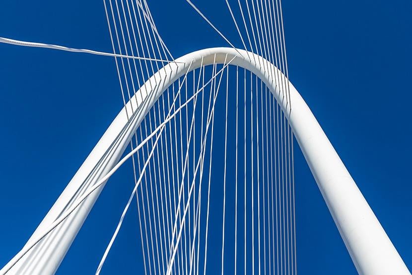 bright white suspension bridge against a deep blue sky