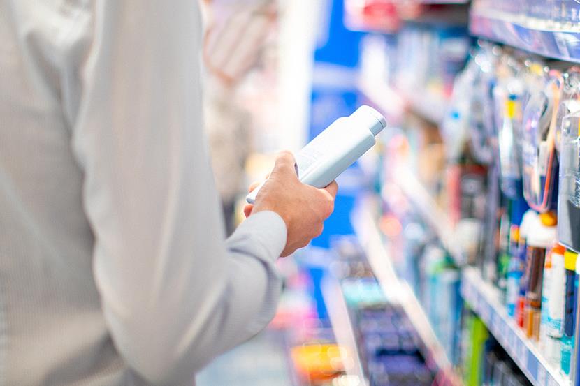 man holding product bottle standing in store aisle